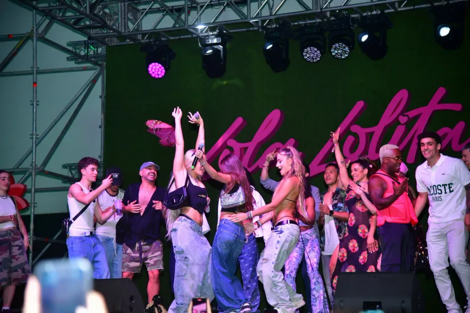 Lola Índigo y otras dos chicas cantando y bailando sobre el escenario.