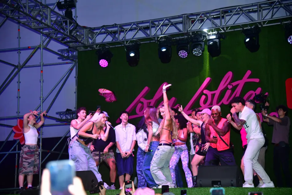 Lola Índigo y otras dos chicas cantando y bailando sobre el escenario.